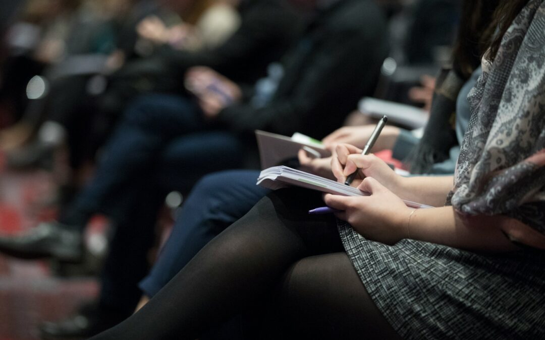 Woman taking notes on paper at conference.