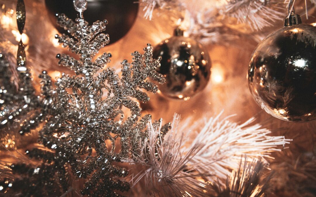 Glittery holiday ornaments on a white tree up close